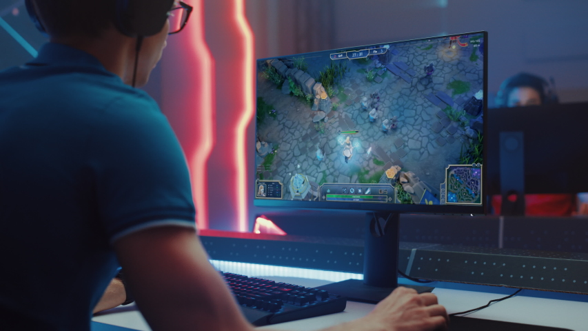 Professional eSports Gamer Plays RPG MOBA Mockup Video Game with Super Action and Fun Special Effects on His Personal Computer. Cyber Gaming Tournament  Championship. Over the Shoulder Camera Shot