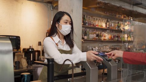 Woman customer paying touchless credit card to waitress with face mask on counter then next customer come and order food by social distancing rule for new normal lifestyle in restaurant during covid.