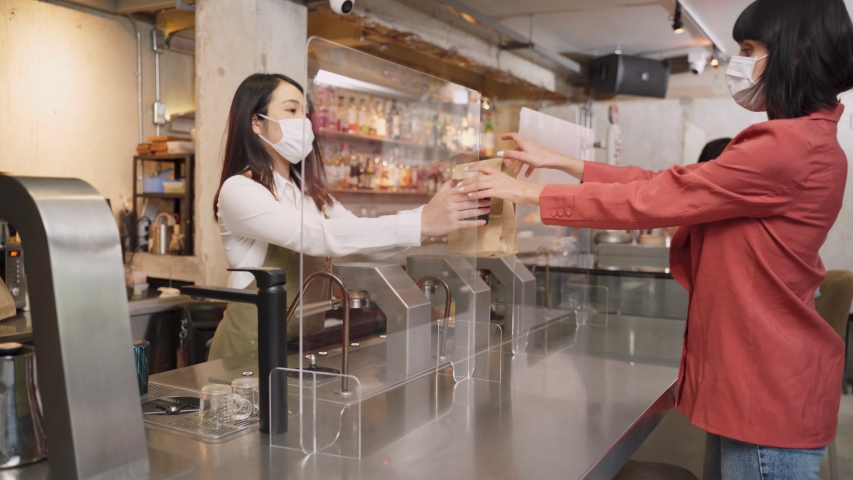 Woman customer receiving food from waitress with face mask on counter then next customer come and order food by social distancing rule for new normal lifestyle in restaurant during covid pandemic. | Shutterstock HD Video #1058266723