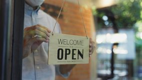 Cafe or restaurant and business reopen after Coronavirus quarantine is over. Man with face mask turning a sign from closed to open on a door shop. Small food shop business after post covid lockdown. - Powered by Shutterstock - Get 15% off with code: PIKWIZARD15