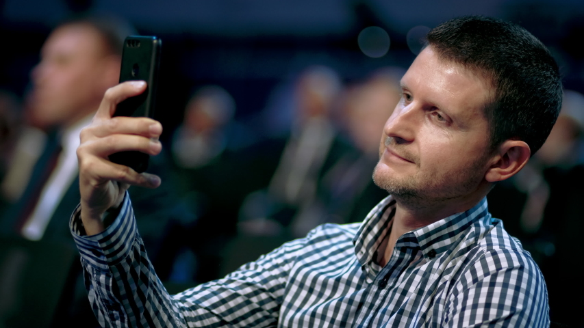 Person take photo on phone in crowded audience business forum. Conference business man with mobile. Seminar for viewer auditorium. group people listen speaker speech. Taking photography scene on phone