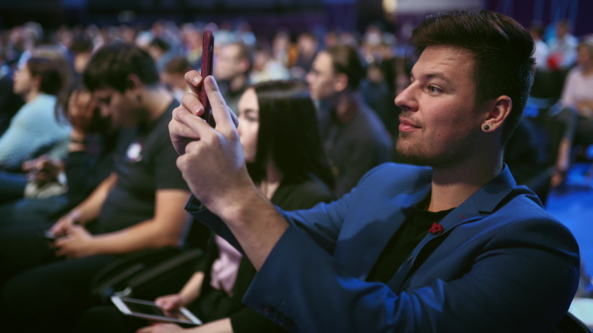 Person take photo on phone in crowded audience business forum. Conference business man with mobile. Seminar for viewer auditorium. group people listen speaker speech. Taking photography scene on phone