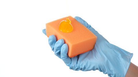 Dishwashing Liquid pouring on kitchen sponge. Hands of woman holding a kitchen sponge with few drops of dish wash gel. household work concept