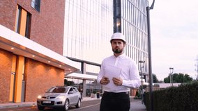 Walking frame with a handsome engineer wearing a helmet and holding a business plan. The engineer analyzes the works and makes notes in his notebook. - Powered by Shutterstock - Get 15% off with code: PIKWIZARD15