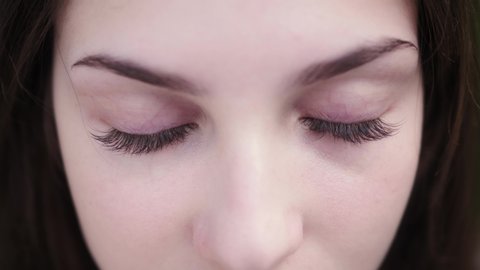 Close up of face. Girl opening her eyes. Beautiful woman with long eyelashes looking at the camera and smiling. Female nature beauty.