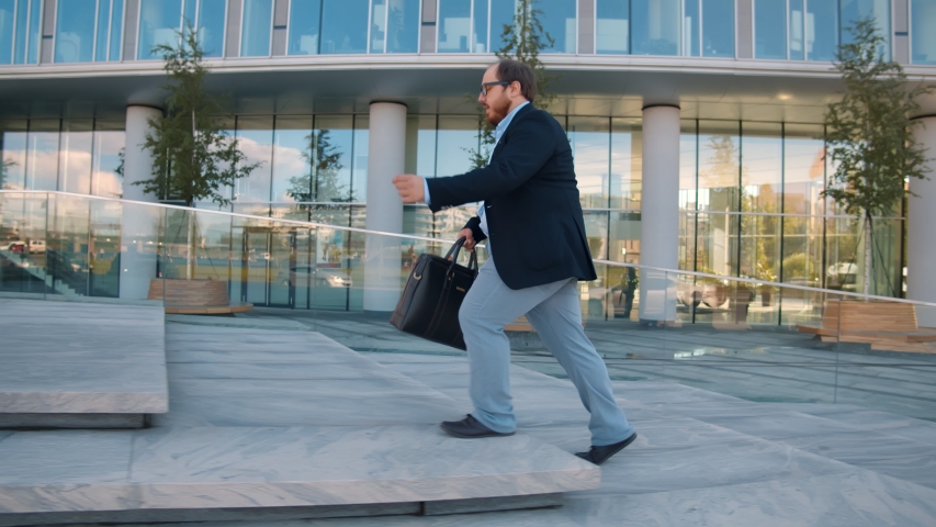 Fat businessman in formal suit running up stone stairs near office building being late. Overweight office manager hurry to business meeting with clients running near business center Royalty-Free Stock Footage #1058281684
