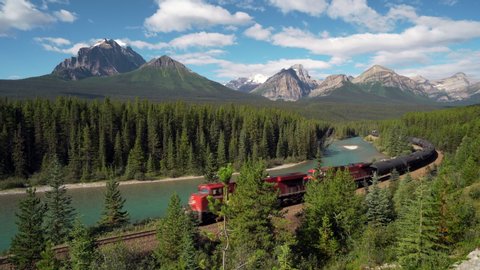 Red cargo train passing through Morant's curve in Bow Valley, Banff National Park, Alberta, Canada. Iconic landscape and railway system in the Rocky Mountains of North America.