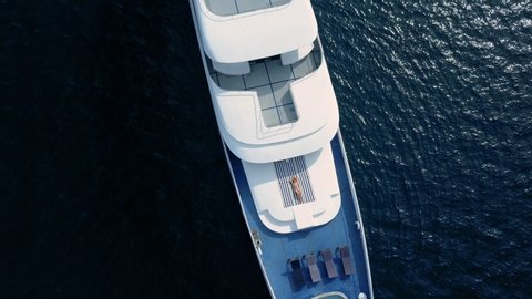 Drone top view on sensual sexy woman lay on deck of beautiful white boat. Private yacht cruise ticket lifestyle enjoying life in open sea. Rich and famous stars and celebrities