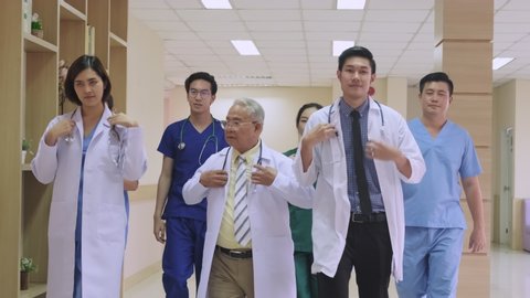 Group of Asian team of doctors, nurses and assistants walking through the hallway of the hospital. Professional medical experience doctors walking indoor and working for save the lives. Slow Motion. 