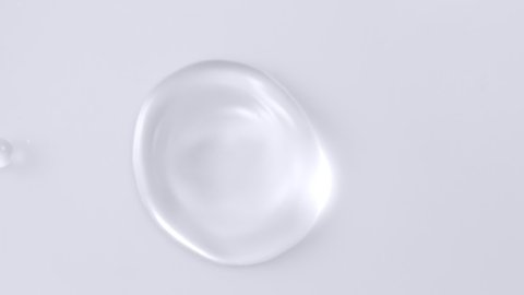 Slow motion and super macro shot of a crystal clear water droplet bouncing and moving around on a white surface 