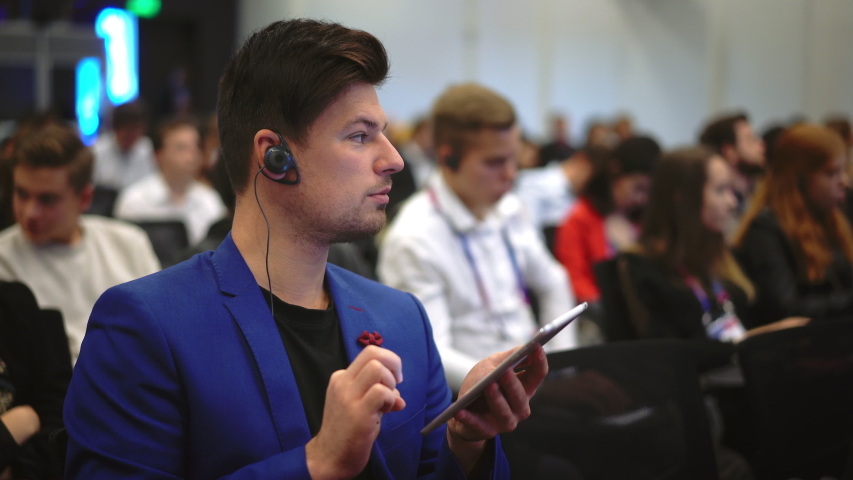 Person type touch screen crowded audience business forum. Viewer seminar listen speaker auditorium. Business man typing hand pad political summit. Group people learning speech in crowd audience.