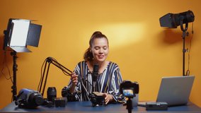 Influencer woman reviewing a new fluid head in professional studio. Social media star making online internet content about video equipment for web subscribers and distribution, digital vlog talking