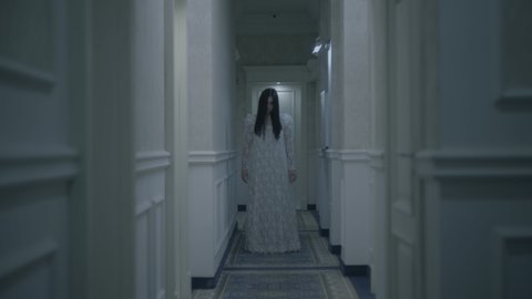 Terrible zombie bride walking long hallway possessed by evil spirit horror night.