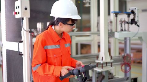 Female engineer use robot pendant to configuration the industrial robot  in factory.