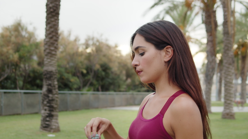 Hispanic woman drinking water from bottle after gym, outdoor workout, city sport, brunette latin girl drink clear mineral water after jogging. Generation z lifestyle. Royalty-Free Stock Footage #1058301547