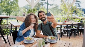 Happy couple sitting outdoors on terrace restaurant, taking selfie. - Powered by Shutterstock - Get 15% off with code: PIKWIZARD15