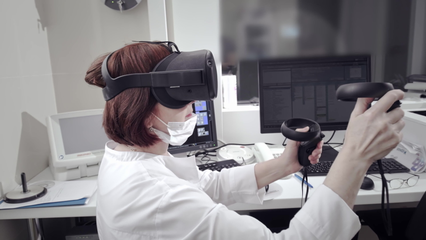 Futuristic Concept: In Medical Laboratory Surgeon Wearing Virtual Reality Headset Uses Controllers to Remotely Operate Patient with Medical Robot. High-Tech Advancements in Medicine | Shutterstock HD Video #1058307256