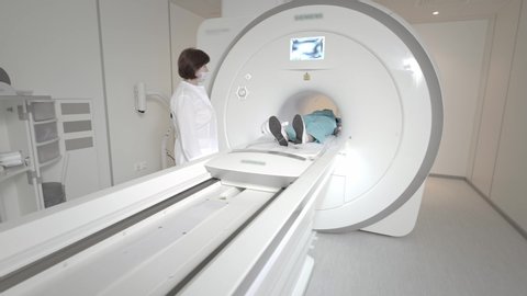 Doctor makes an MRI scan for a patient in a clinic. The girl lies in the MRI device. Magnetic resonance imaging in the study of the human body. Modern technologies in medicine. Examines lungs
