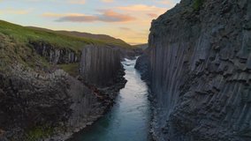 Flying through the Studlagil Canyon with the Jokulsa A Bru river in east Iceland, Europe. Filmed at sunset. 4K UHD video.
