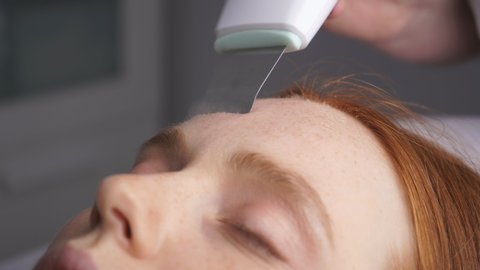 Young woman receives an ultrasound facial cleaning from a cosmetologist in a Spa salon. close-up