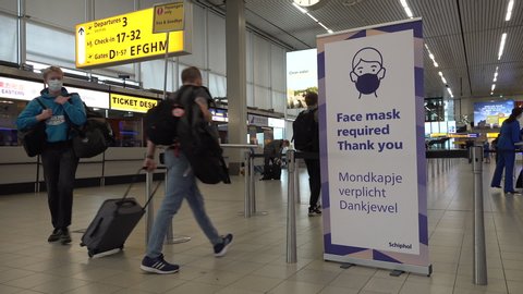 SCHIPHOL, NETHERLANDS – AUGUST 2020: Sign informs air travel passengers that face masks are required during check-in procedure at Amsterdam Schiphol Airport in the Netherlands, Covid-19 coronavirus 