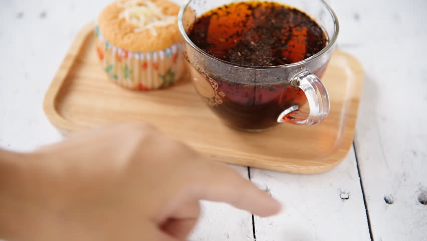 Hand and momon cake with cup of tea on table