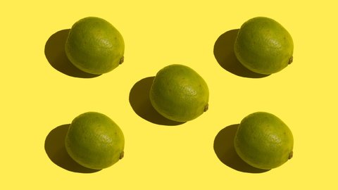 Stop motion Five green limes spin on their axis on a yellow background