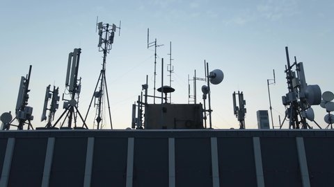 Skyscraper antennas and communication radars on building rooftop, aerial reveal
