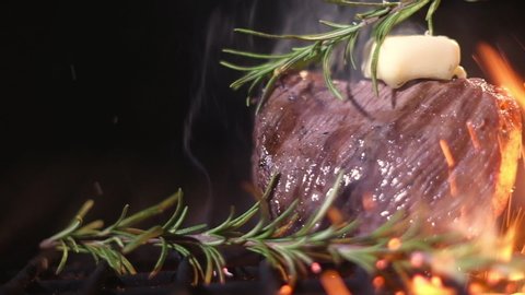 tenderloin is fried on grate at picnic. cooking delicious steak on fire in sparks of flame. Juicy meat on grill. beef steak is prepared with branch of rosemary and piece of butter on grill