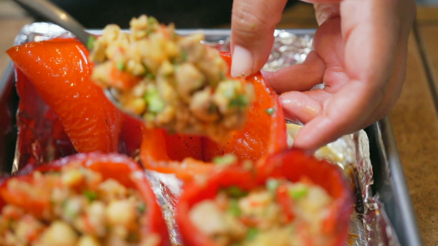 Isolated macro view of stuffing red sweet bell peppers with a savory vegan mixture - slow motion