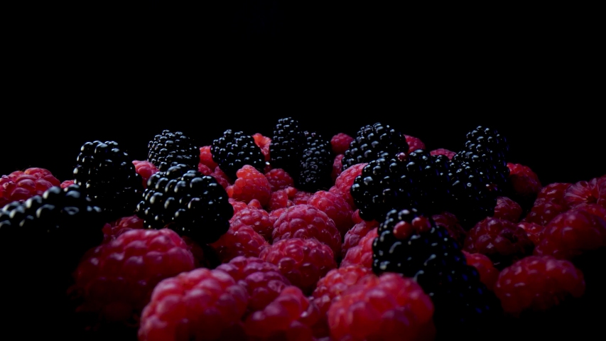 Blackberries and raspberries on a black background. Composition of a raw and fresh forest fruits close up in 4K. | Shutterstock HD Video #1058326873