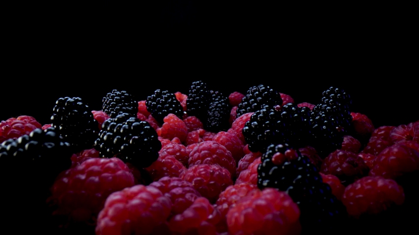 Blackberries and raspberries on a black background. Composition of a raw and fresh forest fruits close up in 4K. Royalty-Free Stock Footage #1058326873