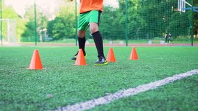 Football concept where concentrated sporty junior football player running around the orange racks that standing on the artificial turf on the stadium during workout - Powered by Shutterstock - Get 15% off with code: PIKWIZARD15