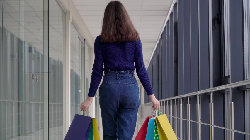 Young girl with with colorful shopping bags walking in a shopping center. Safe shopping