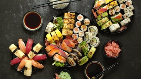 Asian food fest. Menu sushi with nigiri, maki, uramaki on black plates. Various kinds of sushi served on a dark background.