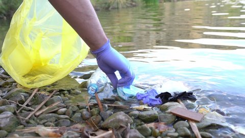 Close Up of Person Collecting Mask and Gloves From the River. Man Cleaning River of Plastics. Environment Concept.