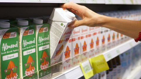 Choosing plant based milk in grocery store .Picking up different options of vegan milk from the shelf and reading the labels. Healthy vegan lifestyle. 2020- Warsaw- Poland