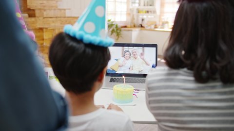 Happy cheerful Asian family having fun celebrating birthday with parents and grandparents on video call at home. Spending time together, Social distancing, Quarantine for corona virus prevention.