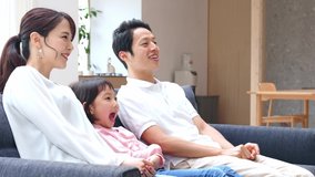 Asian family watching TV in living room.