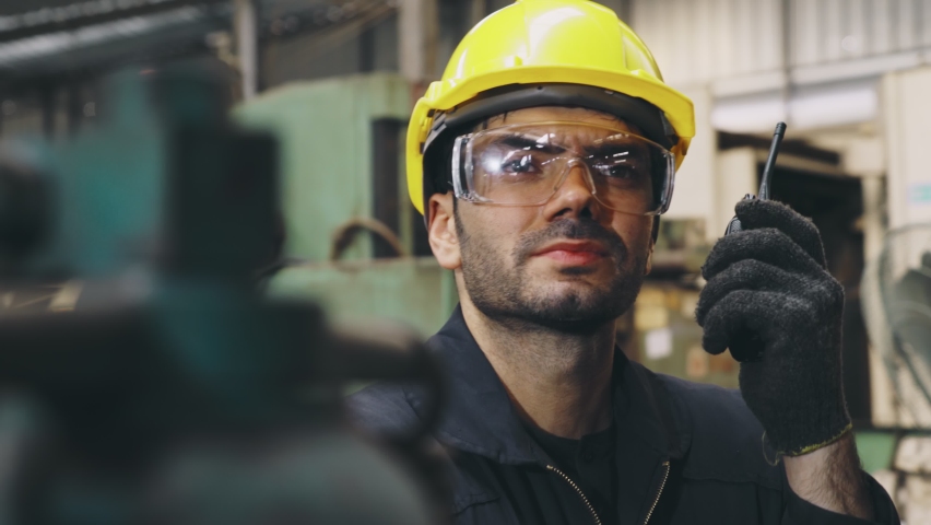 Factory worker talking on portable radio while inspecting machinery parts . Industrial and engineering team communication concept . | Shutterstock HD Video #1058357095