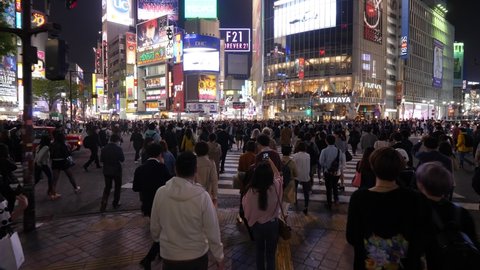 TOKYO - APRIL 03, 2018: Shibuya diagonal crosswalk at night, first person view camera walk with crowd. Overhead shot of moving mass of people, lively scramble at pedestrian crossing