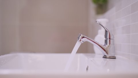 Man's hand closes the open water tap. Save energy, save water. Preserve natural resources