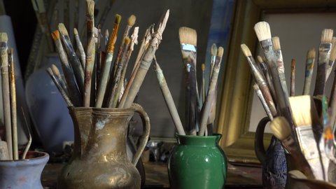 Artist's art tools in the Studio. Oil paintings in creative workroom. Brushes, paints, palette, canvas, easel