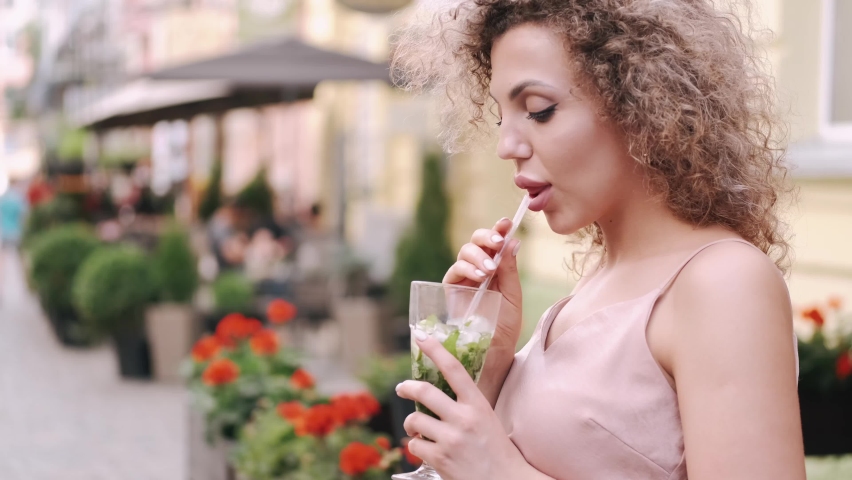 A beautiful woman is drinking a cocktail in the summer city. Summer holiday concept