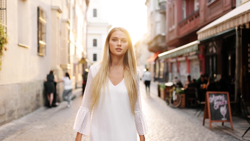 Portrait young attractive smile woman look at camera at city center. Outdoor portrait happy female tourist having good time wandering around town in summer. Royalty-Free Stock Footage #1058366314
