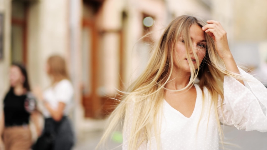 Beautiful woman with a magnificent golden hair. Fun happy young girl shake her head to make hair flying. Attractive young lady turns around and looks into the camera
