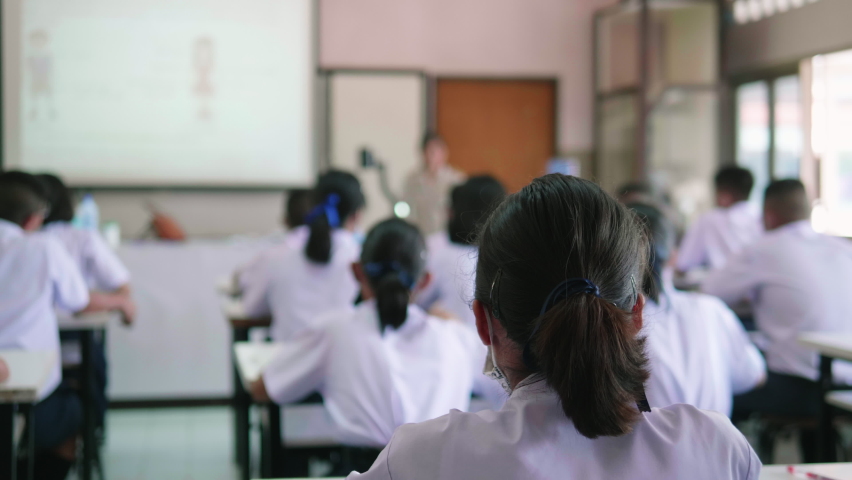 Slow motion of Asian high school students in white uniform actively study science by raising their hands to answer questions on projector screen that teachers ask them  in science classroom. Royalty-Free Stock Footage #1058371012