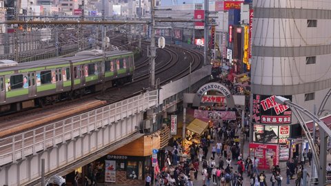 TOKYO - APRIL 04, 2018: Typical Ameyayokocho view, elevated railway and busy shopping street beneath. Train ride at viaduct, many people walk at popular open-air market near Ueno station