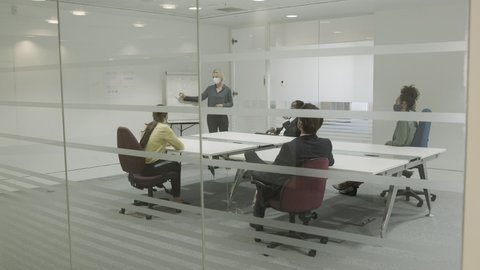 Business people meeting in boardroom wearing protective face mask for presentation