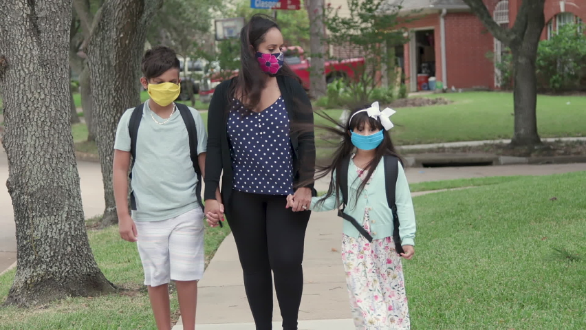 Prerequisite for in classroom instruction and the new normal during COVID19 pandemic is mask wearing as demonstrated by this mother and her children as she walks them to the school bus stop.